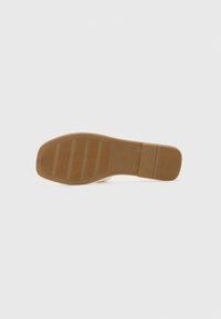 Shoe sole with ridged brown rubber, featuring a flat area and textured patterns for grip. Minimalist design with a smooth edge.