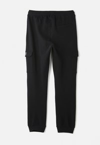 Pantalons de survêtement cargo noirs en tissu doux, dotés d'une taille élastique, de poches latérales et d'une poche arrière simple avec une texture lisse.