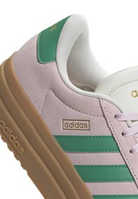 Adidas sneakers met een bovenwerk van roze suède, groene leren accenten, witte veters en een gumrubberen zool. Logo weergegeven op de zijkant.
