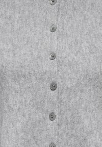 Sivi kardigan od mekog pletenog materijala s lagano teksturiranom površinom. Ima šest kopči na gumbe u istoj sivoj boji.