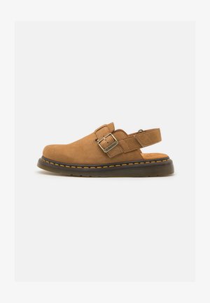 Brown suede slip-on sandal with a strap and buckle detail, featuring a thick black rubber sole with yellow stitching.