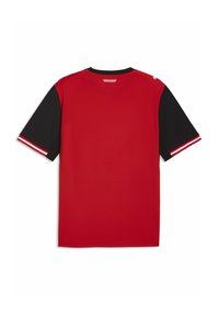 Κόκκινο αθλητικό μπλουζάκι με κοντά μαύρα μανίκια, που διαθέτει λευκές και κόκκινες ρίγες στις άκρες των μανικιών. Το ύφασμα φαίνεται λείο και ελαφρύ.