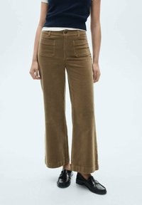 Bruine corduroy wijde broek met een hoge taille, twee voorkoffers en een knoopsluiting. De zoom is boven de enkel afgeknipt.