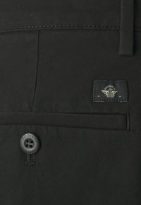 Czarne spodnie materiałowe z zapięciem na guzik oraz metką z logo "Dockers". Tkanina ma gładką fakturę i minimalne detale szwów.