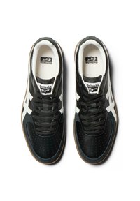 Black and white sneakers with a textured upper, perforations for breathability, and a gum sole. Features laces and branding on the tongue.