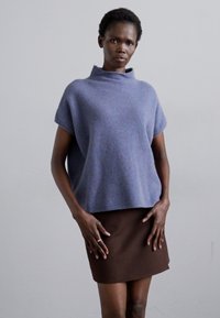 Suéter de lana azul claro con un cuello alto y mangas cortas, combinado con una falda lápiz marrón oscuro, que presenta una textura suave.