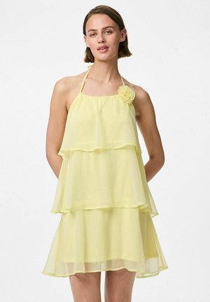 Robe jaune à couches avec un design à col halter, ornée d'une fleur sur l'épaule. Fabriquée en tissu léger et transparent.