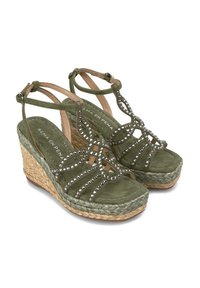 Sandali con zeppa in suede verde, caratterizzati da un design incrociato impreziosito da borchie argentate e una piattaforma e un tacco in juta intrecciata.
