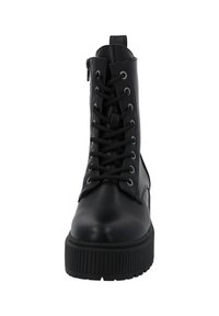 Botas de tobillo de cuero negro con diseño de cordones en la parte delantera, cremallera lateral, punta redonda y suela gruesa y texturizada con ranuras horizontales.