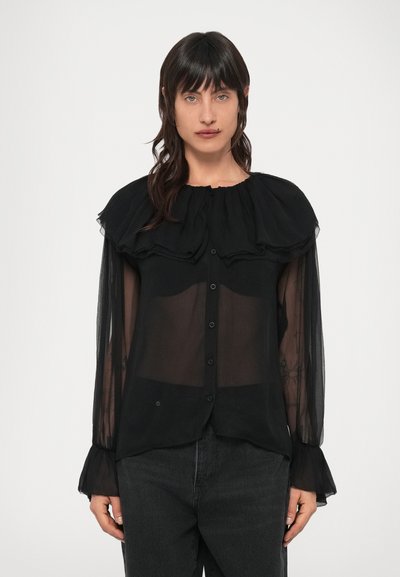 Blouse noire transparente avec un col à volants, des manches longues et une fermeture à boutons. Présente une texture délicate et un tissu légèrement transparent.