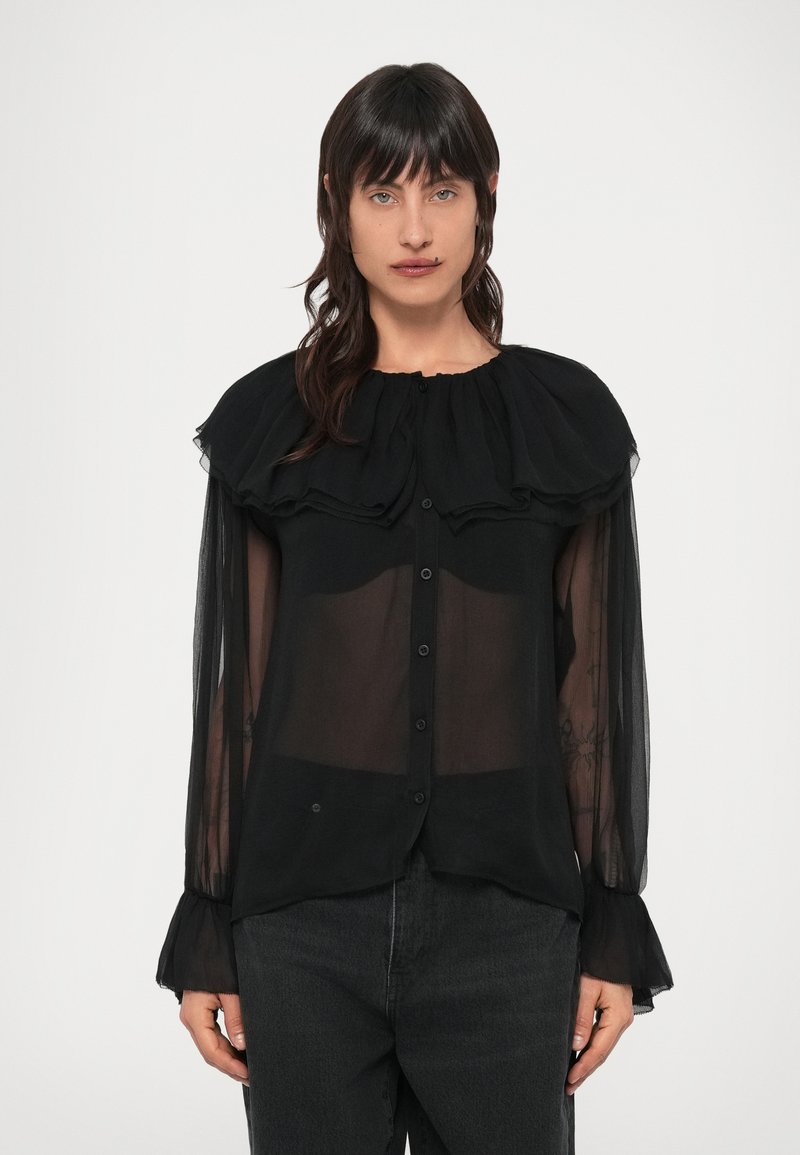 Čierna priehľadná blúzka s volánovým golierom, dlhými rukávmi a zapínaním na gombíky. Má jemnú textúru a mierne priehľadnú látku.