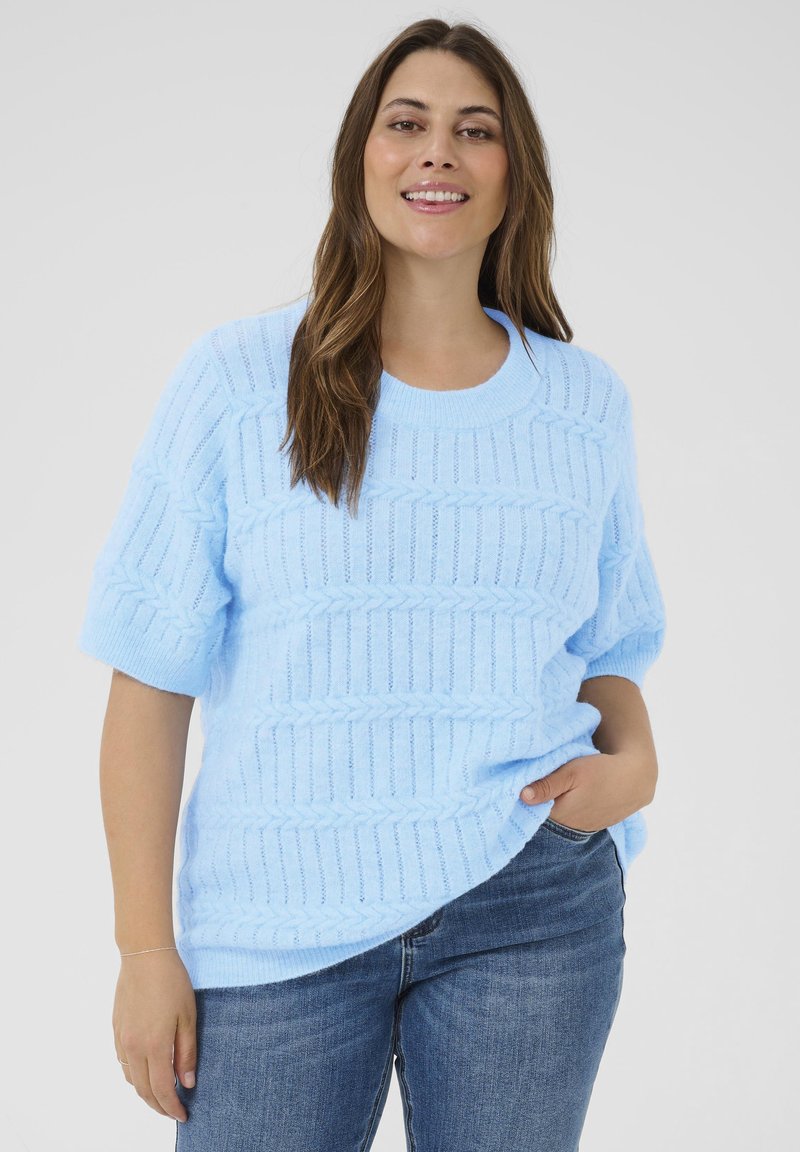 Suéter de punto azul claro con mangas cortas, que presenta un patrón texturizado de líneas en relieve y un cuello redondo. Combinado con jeans azules.