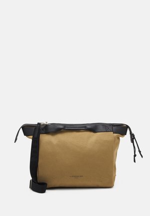 Rechteckige, hellbraune Segeltuchtasche mit schwarzen Lederakzenten, schwarzem verstellbarem Schultergurt, Reißverschluss und kleinem Markenaufdruck auf der Vorderseite.