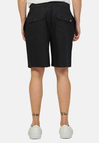 Pantaloni corti neri realizzati in tessuto leggero, con due tasche posteriori con chiusura a bottone e una vita elastica per il massimo comfort.