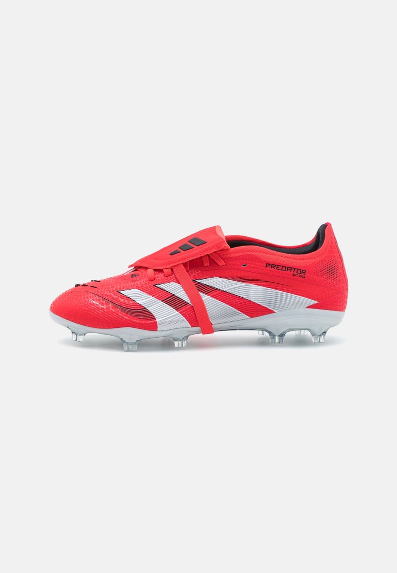 Czerwony korki piłkarskie Adidas Predator z białymi paskami, składanym pokryciem sznurowadeł i przezroczystymi wkrętami, przedstawione z boku na białym tle.