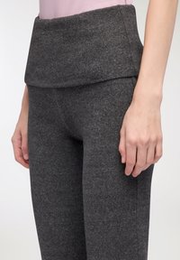 Szare legginsy z wysokim stanem, wykonane z miękkiego, fakturowanego materiału, z szerokim pasem na tyle oraz przylegającym krojem.