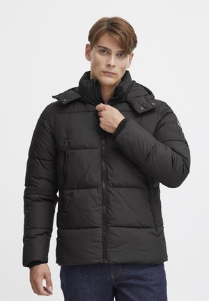 Svart pufferjakke med hette, med et quiltet design, frontglidelås og sidelommer. Stoffet ser glatt og isolert ut.