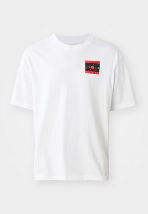 Fehér pamut póló, amelyen egy piros és fekete téglalap alakú grafika látható az "AUTHENTIC JORDAN BY NIKE" felirattal az elülső bal oldalon. Rövid ujjú.