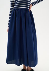 Jupe maxi bleu marine avec une taille froncée, en tissu léger, présentant une texture lisse et une silhouette fluide.