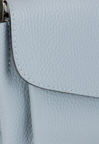 Borsa a tracolla in pelle azzurro chiaro con superficie texturizzata, dotata di chiusura a pattina e dettagli di cucitura a contrasto.