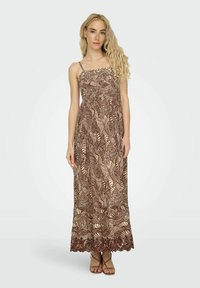 Robe maxi avec un motif de feuilles brun et beige, présentant des bretelles fines, un corsage smocké et un ourlet en dentelle.