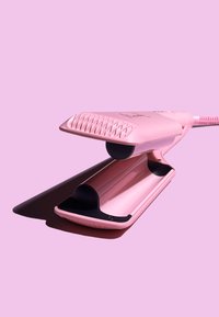 Plancha de pelo rosa con un agarre texturizado, placas de cerámica suaves y forma redondeada. Cable de alimentación adjunto, diseño minimalista.