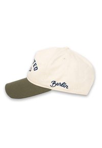 Căciulă de baseball cu corp din bumbac crem și vizieră verde. Are textul brodat "United" și "Berlin" în nuanță de bleumarin. Curea reglabilă la spate.