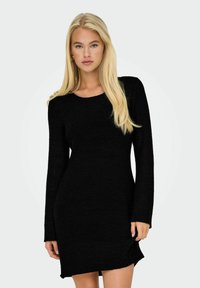 Robe noire en tricot à manches longues avec un col rond, dotée d'un motif texturé et d'une coupe légèrement oversize, se terminant au-dessus des genoux.