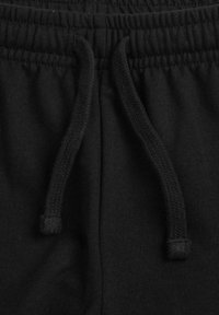Pantalon de jogging noir avec une taille élastique et un cordon de serrage. Confectionné en tissu doux, présentant une texture lisse sans motifs ni éléments visibles.