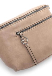 Beige lædertaske med en struktureret overflade, har to vandrette lynlåse og et dekorativt hardwareelement på lynlåsens træk.