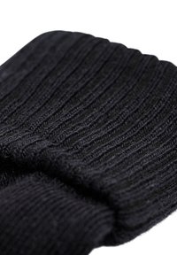 Schwarze gerippte Socke aus weich gestricktem Material. Verfügt über ein strukturiertes Design mit einem dicken Bündchen. Glatte Oberfläche mit subtilen Variationen im Garn.
