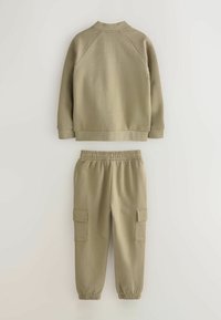 Khaki sviiter raglanvarrukatega ja vale kaelusega, millele on lisatud sobivad kargopüksid elastsete mansettidega ja küljetaskutega.