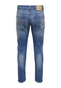 Μπλε ξεθωριασμένο τζιν με πίσω τσέπες και δερμάτινη ετικέτα του brand στη μέση, εμφανιζόμενο από πίσω.