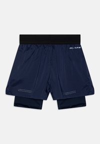 Tummansinisiä urheilushortseja mustalla elastisella vyötärönauhalla, joissa on kerroksellinen muotoilu ja pienet reikämäiset yksityiskohdat helmassa.