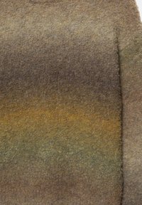 Tessuto lavorato a maglia con una gradazione di marroni, verdi e gialli smorzati. Superficie morbida e testurizzata con un aspetto leggermente peloso.
