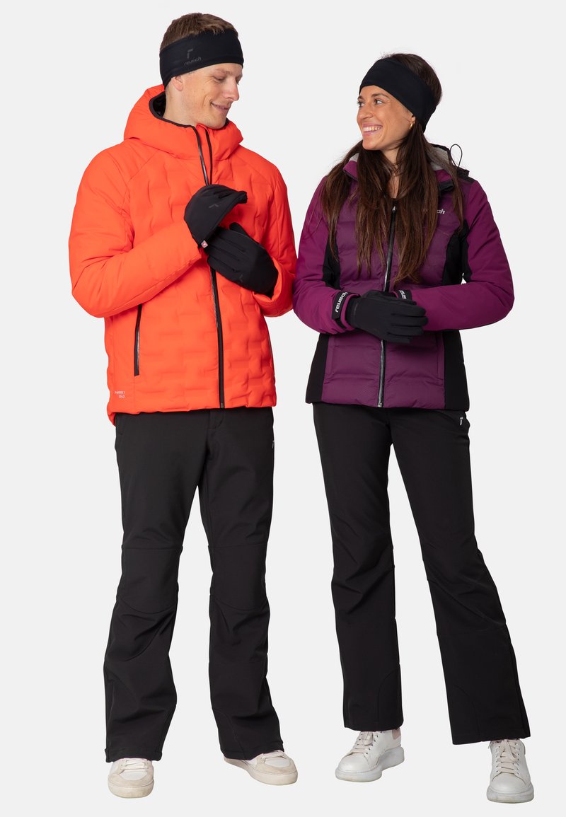 Two individuals wearing outdoor gear: one in an orange padded jacket, black gloves, and black pants; the other in a purple insulated jacket and black pants.