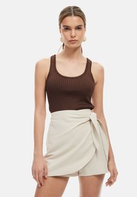 Bruine geribde tanktop gecombineerd met een crèmekleurige wrap-stijl short, met een geknoopt accent aan de taille en een soepele textuur.