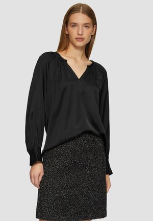 Zwarte zijden blouse met een V-hals, geplooide lange mouwen en een relaxte pasvorm, gecombineerd met een gestructureerde zwarte rok met metallic accenten.