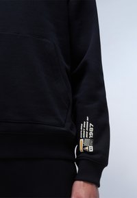 Felpa nera con tasca a marsupio, polsini a costina e una grafica lucida sulla manica con testo e logo in bianco e oro.