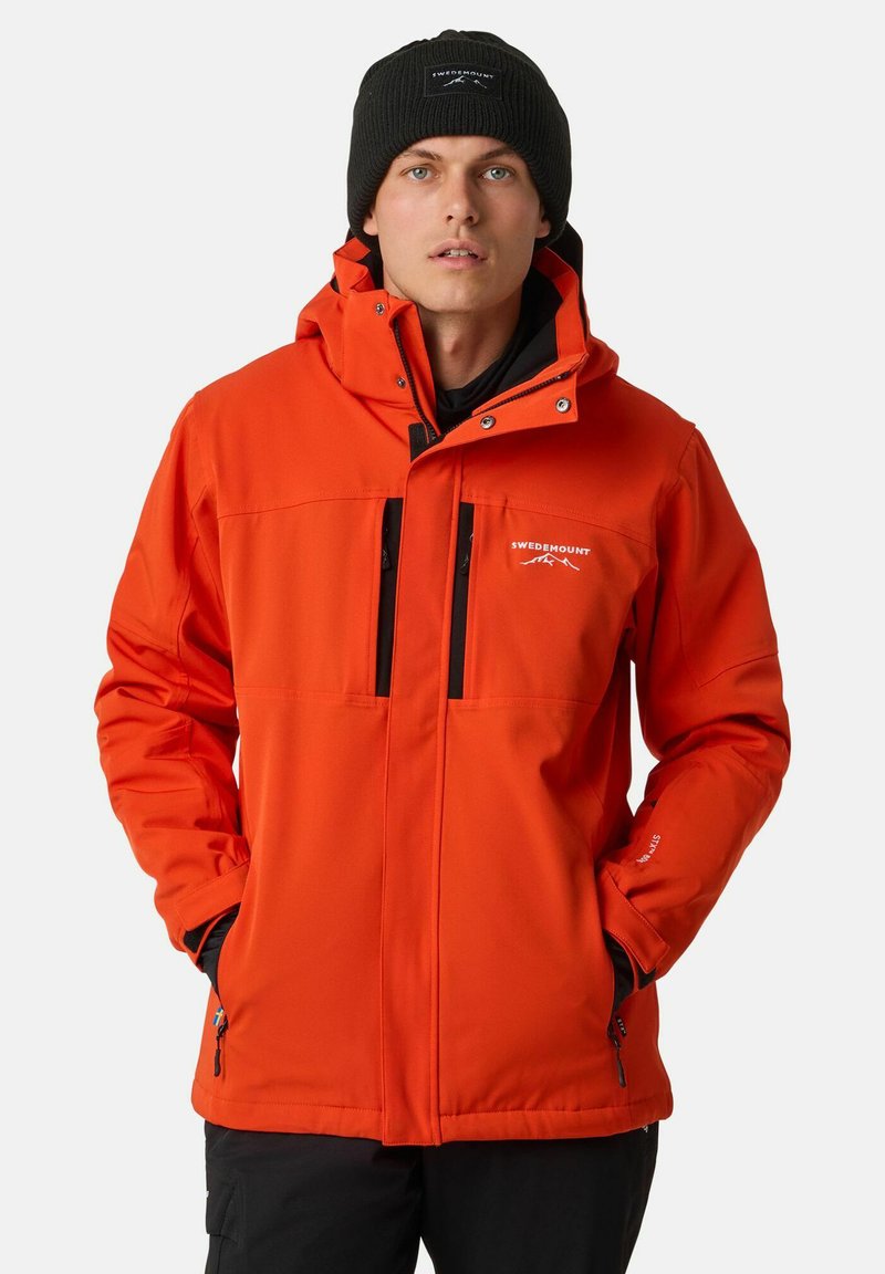 Helle orange, wetterfeste Jacke mit Reißverschluss vorne, Kapuze und zwei schwarzen Reißverschlusstaschen. Mit verstellbaren Bündchen und Logodetail.