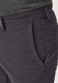 Dunkelgraue Baumwollhose mit glatter Textur, schrägen Seitentaschen und einem strukturierten Bund mit dezenten Steppnähten.