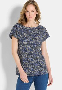 Blouse à manches courtes avec un motif bleu, gris et vert, dotée d'un col rond et d'une coupe ample, fabriquée en tissu léger.