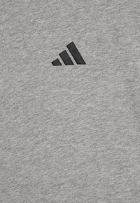 Sudadera gris hecha de una tela suave que presenta un logotipo negro de Adidas aplicado en la parte superior izquierda. Diseño sencillo con una textura suave.