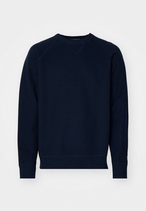 Felpa blu navy con tessuto a trama, scollo rotondo e maniche raglan. Presenta polsini e orlo a coste. Branding minimale sulla manica.