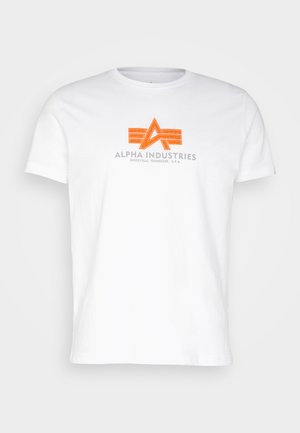 T-shirt bianca in cotone con stampa grafica arancione e grigia, che presenta il testo "ALPHA INDUSTRIES" sotto un logo stilizzato.