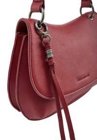 Sac à bandoulière en cuir rouge avec une surface texturée, une quincaillerie argentée et un détail décoratif en forme de gland sur la sangle.