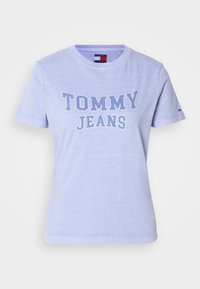 Šviesiai violetinė medvilninė marškinėliai trumpomis rankovėmis ir apvalia iškirpte, su kontrastingai mėlynu spaudiniu "TOMMY JEANS" ant priekio.