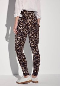 Leggings con stampa leopardata in tessuto morbido ed elastico, con vita alta e design aderente, abbinati a sneakers bianche.