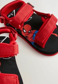 Röda sandaler med en Spider-Man-grafik. Har justerbara tygremmar och en strukturerad svart sula. Lättviktig design med ett lekfullt tema.