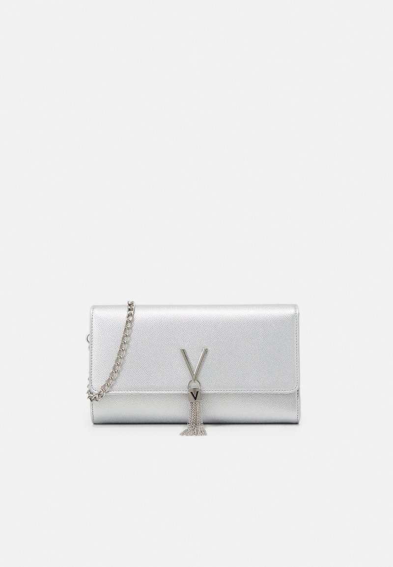 Pochette en cuir argenté avec fermeture à rabat, détail métallisé en forme de V, pompon en chaîne et bandoulière chaîne argentée sur fond uni.